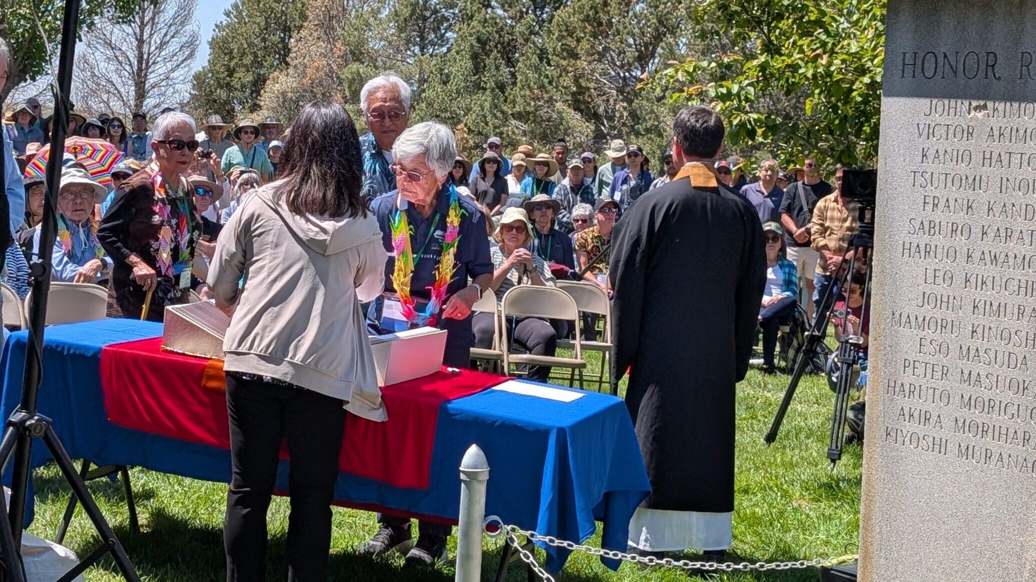 Amache survivors stamp the Ireichō at the cemetery while names are of those who died at Amache are read by Duncan Ryuken Williams. Photo courtesy Kirsten Leong, Amache Alliance.